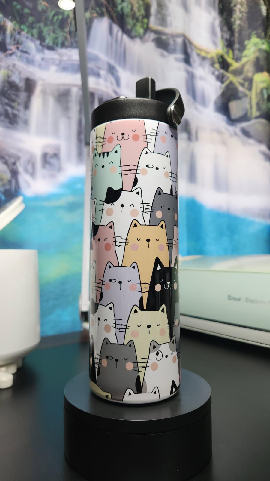 Tumbler with cat pattern on a black stand against a blurred natural background