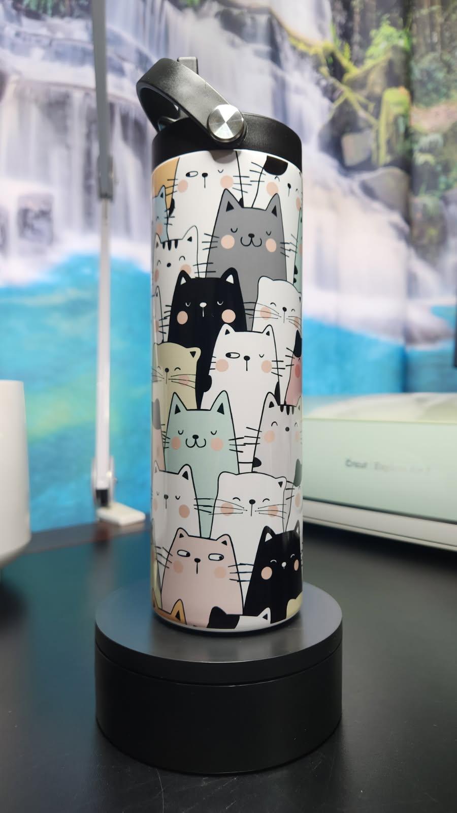 Water bottle with cat pattern on a black stand against a scenic background