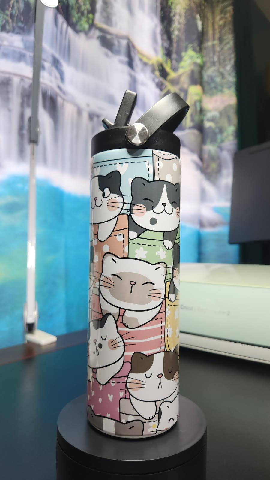 Water bottle with cat pattern on a black stand against a blurred background