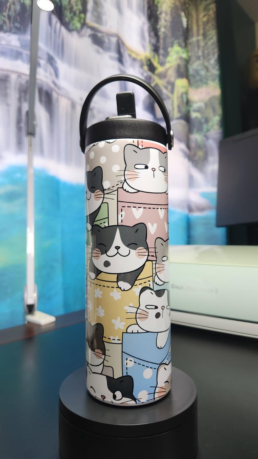 Tumbler with cat pattern on a black stand against a blurred background