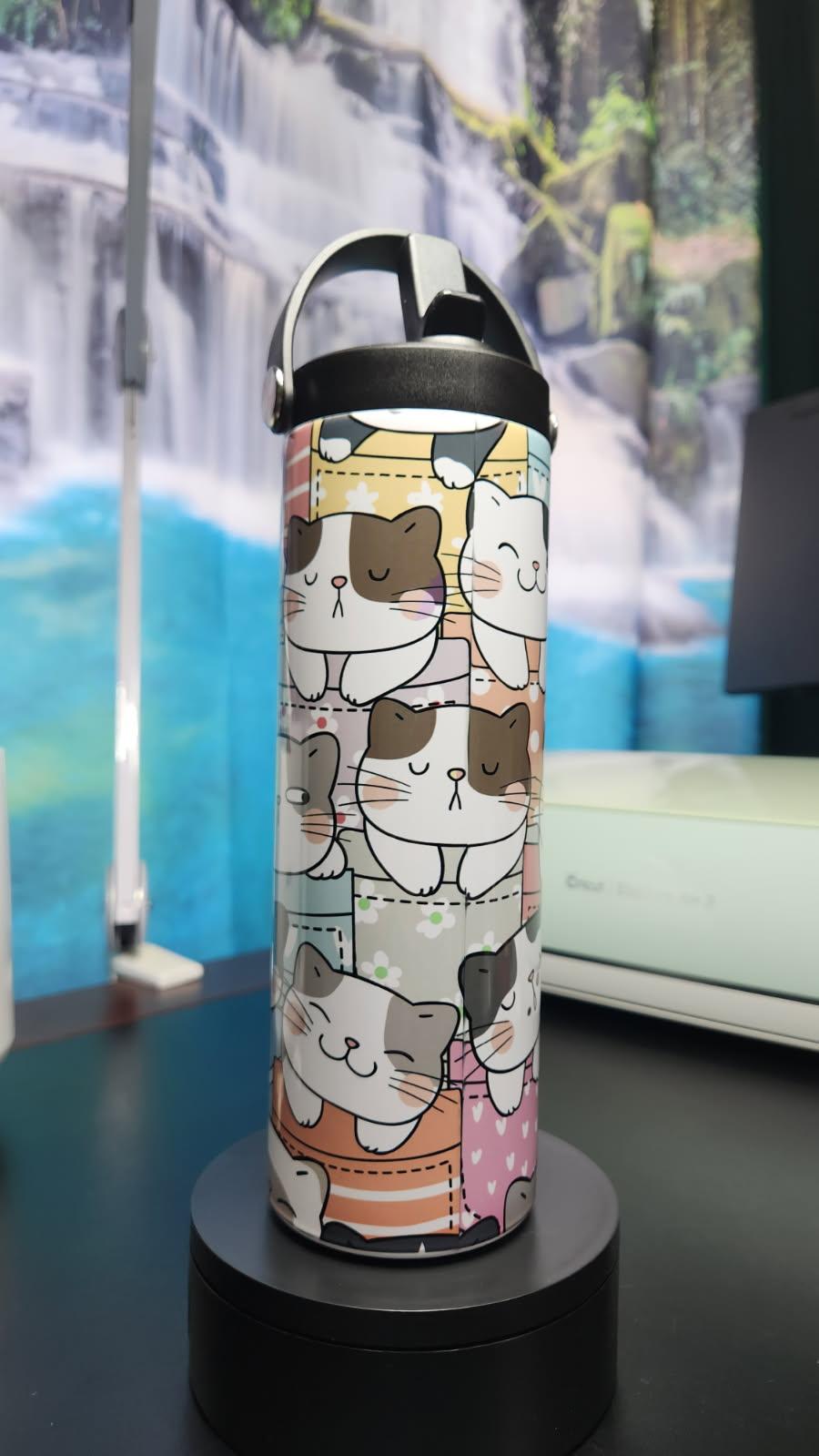 Thermos bottle with cat pattern on a black stand against a blurred background
