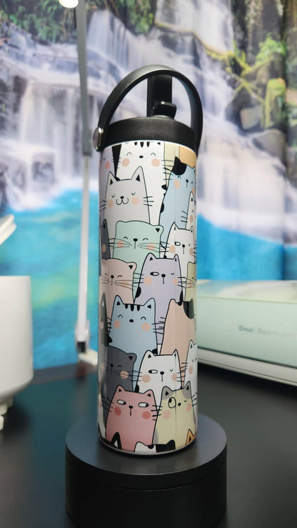 Thermos bottle with cat pattern on a black stand against a scenic background