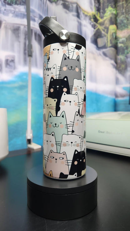 Water bottle with cat pattern on a black stand against a scenic background